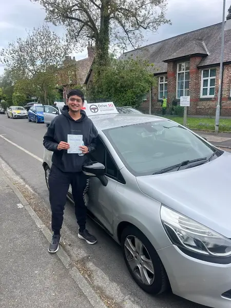 Smiling learner with their pass certificate by a DriveSQ car